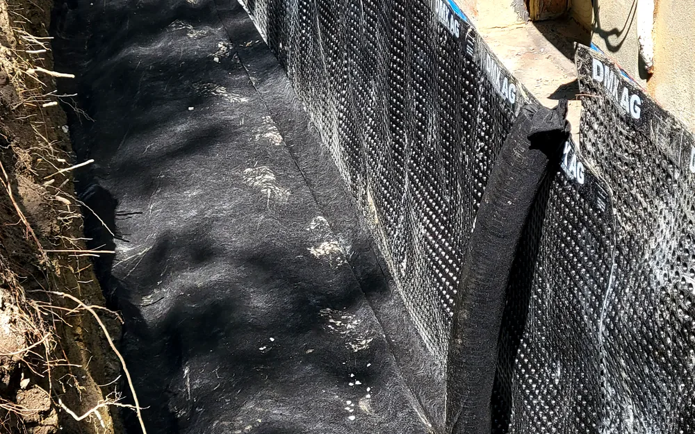 Exterior dimple-board waterproofing membrane installed along a full foundation wall