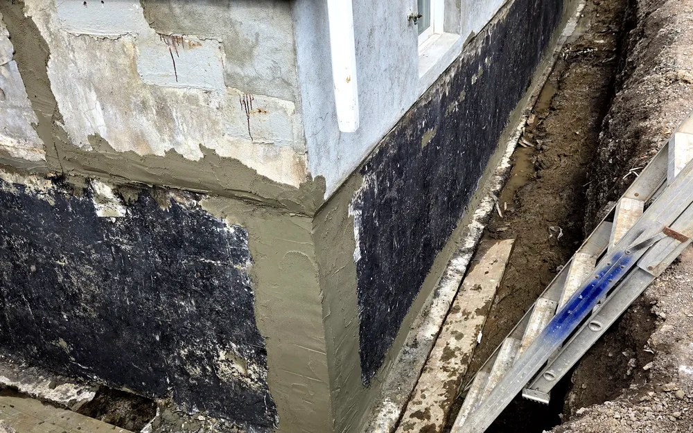 Freshly parged foundation wall showing the new finish
